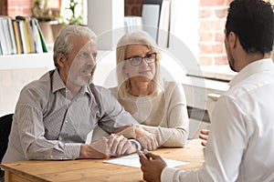 Happy mature couple meeting with financial consultant in office