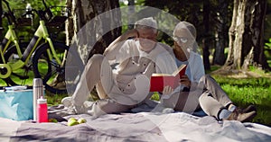 Happy mature couple reading book together and having picnic in park