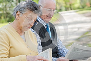 Happy mature couple reading newspaper outdoors