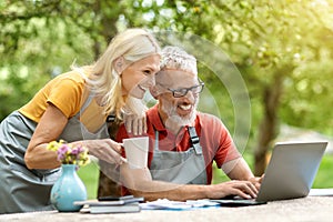 Happy Mature Couple Relaxing With Laptop At Home Terrace Outdoors