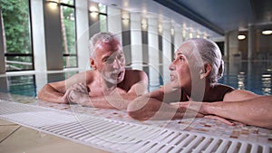 Happy mature couple relaxing on pool side indoors