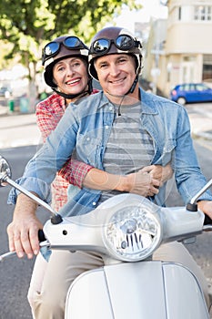 Happy mature couple riding a scooter in the city