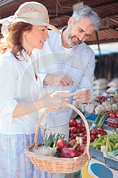 Happy mature couple shopping for groceries in a local organic marketplace