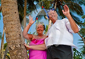 Happy mature couple with snorkeling gear waving