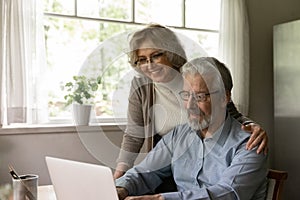 Happy mature couple studying internet application on laptop