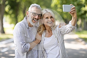 Happy Mature Couple Taking Selfie On Smartphone While Walking In Park