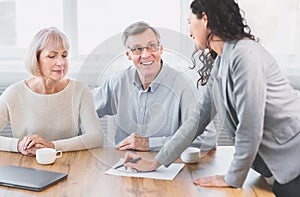 Happy mature couple talking to financial advisor at office