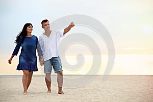 Happy mature couple  together on sea beach at sunset. Space for text