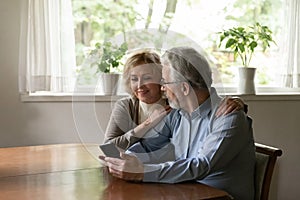 Happy mature couple use smartphone gadget at home photo