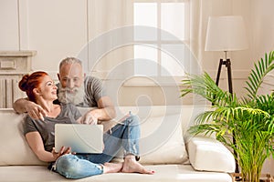 Happy mature couple using laptop together at home