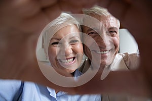 Happy mature elder couple portrait with hand heart shaped frame