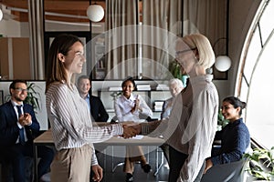 Happy mature female business leader shaking hand of new employee