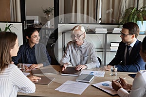 Happy mature female business leader talking to team, giving instructions