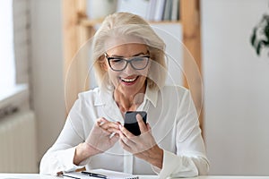 Happy mature female texting on cellphone gadget