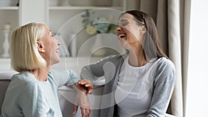 Happy mature grandmother and granddaughter chatting, laughing at joke