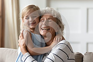Happy mature grandmother and little granddaughter relax at home