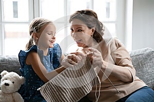 Happy mature grandmother teach small granddaughter knitting photo