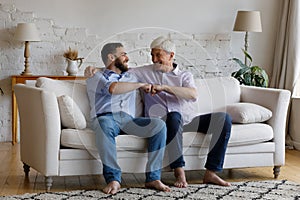 Happy mature grey haired dad congratulating adult son on success