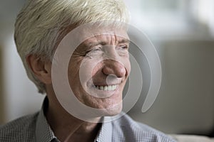 Happy mature grey haired man looking away with toothy smile