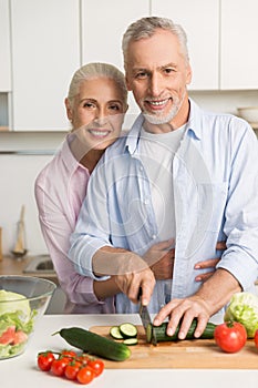 Happy mature loving couple family cooking salad