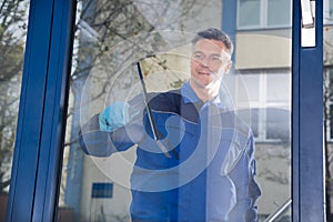 Male Worker Cleaning Glass With Squeegee