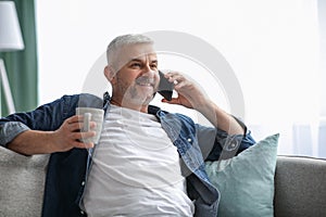 Happy mature man having conversation on smartphone at home