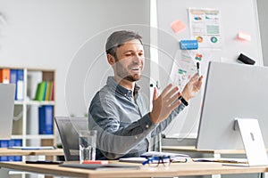 Happy mature man making presentation, demonstrating graphs and charts in office, talking at computer webcamera