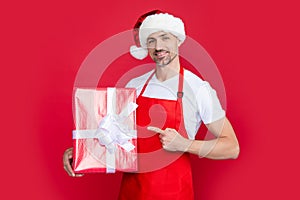happy mature man in santa hat and red apron hold gift
