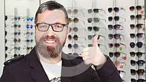 Happy mature man showing thumbs up at the eyewear store