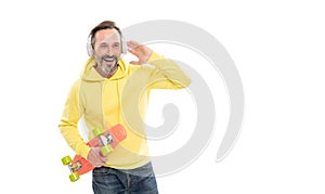 happy mature man skateboarder listen music wearing headphones hold penny skateboard, streetwise.