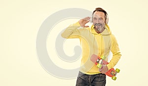 happy mature man skateboarder listen music wearing headphones hold penny skateboard, streetwise. photo