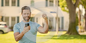 happy mature man standing outdoor at house reading message on smartphone, real estate