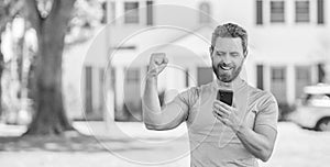 happy mature man standing outdoor at house reading message on smartphone, real estate