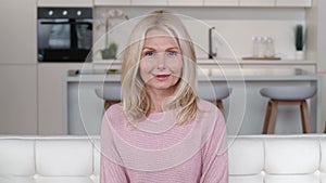Happy mature middle aged woman looking at camera posing at home apartment, portrait of smiling older grey-haired female