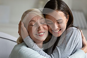 Loving elderly mother and adult daughter hug at home photo