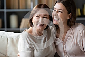 Happy mature mother and adult daughter hugging, having fun