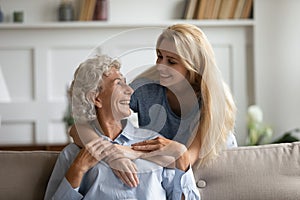 Happy mature mother and adult daughter relax at home