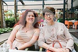 Happy mature mother and her adult daughter enjoying in conversation while spending Mother's day together in a cafe