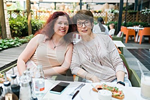 Happy mature mother and her adult daughter enjoying in conversation while spending Mother& x27;s day together in a cafe