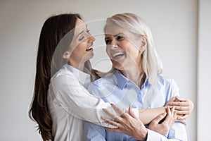 Happy mature mum and adult daughter have fun at home