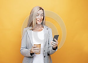 Happy mature old 60s woman with long hair holding smartphone and takeaway coffee