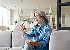 Happy mature old woman holding smartphone using mobile phone app for video call.