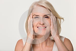 Happy mature woman touching face isolated, anti aging beauty concept photo