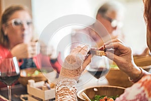 Happy mature people eating at restaurant lunch - Senior friends having fun eating and drinking red wine - Joyful elderly lifestyle