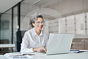 Happy mature professional business woman working on laptop computer in office.