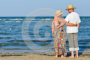 Happy mature romantic couple resting at seashore and embracing