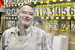 Happy mature salesperson in hardware store looking away