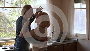 Happy mature senior couple dancing laughing in the kitchen