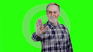 Happy mature senior man shows his palm as stop gesture sign.