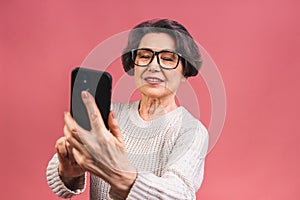 Happy mature senior woman holding smartphone using mobile online apps, smiling old middle aged grandmother texting sms message